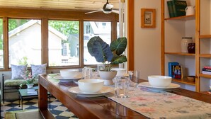A dining area with a wooden table set for four, a potted plant, and a bookshelf with books and decorative items. - Lakeside retreat minutes walk from Douglas Beach! (Douglas)