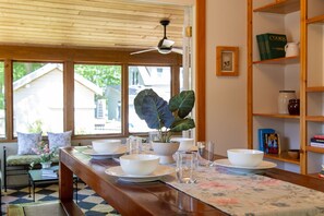 Ein Essbereich mit einem Holztisch, gedeckt für vier Personen, einer Zimmerpflanze und einem Bücherregal mit Büchern und Dekoration.