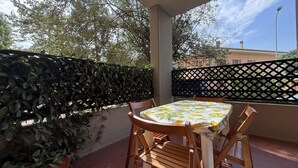 A covered patio with a table and chairs, a black lattice fence, and potted plants. - SE265 – Senigallia, modern one-bedroom apartment with terrace and wi-fi (Senigallia)
