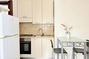 Eine kleine Küche mit Gasherd, Backofen, Spüle und einem Essbereich mit Tisch und Stühlen.