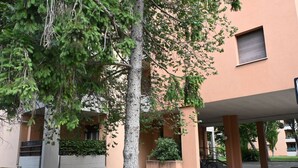 A building with a covered entrance, a tree in front, and a bicycle parked nearby. - SE265 – Senigallia, modern one-bedroom apartment with terrace and wi-fi (Senigallia)