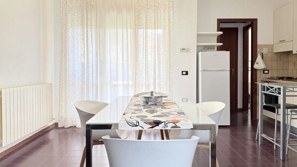 A modern kitchen with a refrigerator, a dining table with chairs, and a kitchen island. - SE265 – Senigallia, modern one-bedroom apartment with terrace and wi-fi (Senigallia)