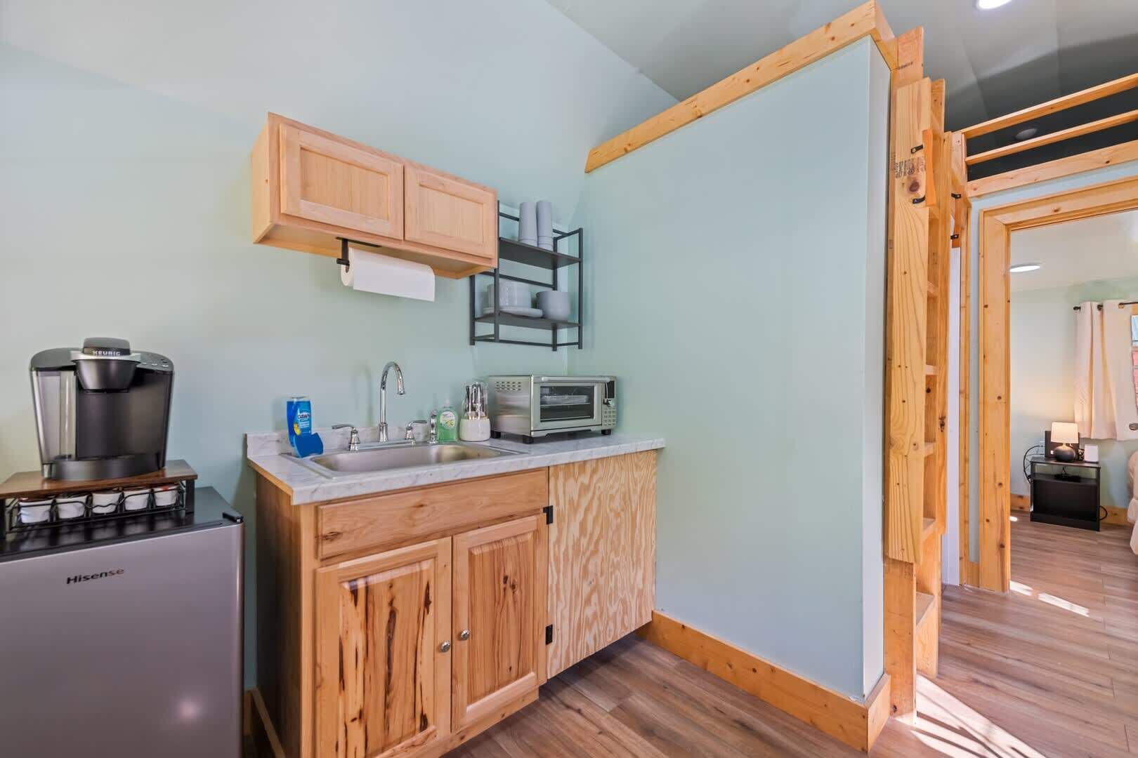 A compact kitchen with a coffee maker, microwave, and wooden cabinets.