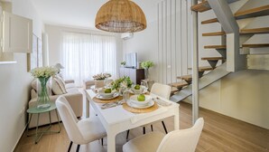 A dining area with a white table set for four, a wicker pendant light, and a staircase with wooden steps. - Refined And Elegant Two-Bedrooms Apartment Near Rocca Del Cerruglio In Montecarlo (Montecarlo)