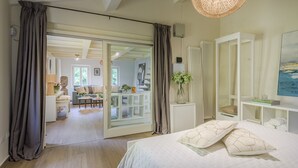 A bedroom with a bed, a large window, a white wardrobe, and a view into the living area. - Refined And Elegant Two-Bedrooms Apartment Near Rocca Del Cerruglio In Montecarlo (Montecarlo)
