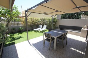 A patio with a table and chairs, a covered seating area, and a small garden. - Chloe by Frangki (Aegina)