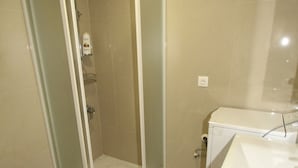 Une salle de bain avec une douche à parois de verre, un lavabo, un bidet et un lave-linge.