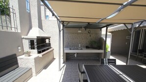 Un espace extérieur aménagé avec un patio, un barbecue, une table et un banc.
