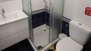 Un baño con ducha, inodoro, lavamanos y espejo.