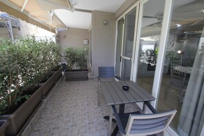 Eine Terrasse mit Tisch und Stühlen, Blumentöpfen und einer Schiebetür zum Balkon.