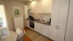 A compact kitchen with a microwave, stove, sink, and cabinets. - Dafne by Frangki (Aegina)