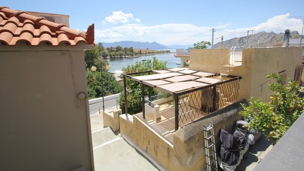A rooftop terrace with a view of a lake and mountains, a tiled roof, and a metal railing. - Dafne by Frangki (Aegina)
