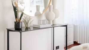A bedroom with a bed, a bedside table with a mirror, and a window with sheer curtains. - Sea-View Terrace: Elegance and Spectacular Views in Viareggio (Viareggio)