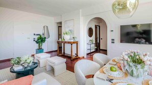 A modern living room with a dining area, a TV mounted on the wall, and a large mirror. - Sea-View Terrace: Elegance and Spectacular Views in Viareggio (Viareggio)