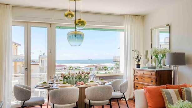 A modern living room with a balcony, a dining area, and a view of the sea. - Sea-View Terrace: Elegance and Spectacular Views in Viareggio (Viareggio)