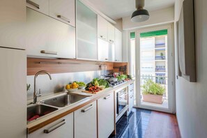 A modern kitchen with a built-in stove, a sink, and a window with a view of a balcony. - Sea-View Terrace: Elegance and Spectacular Views in Viareggio (Viareggio)