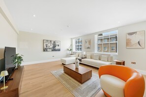 En moderne stue med sofa, sofabord og lænestol i orange.