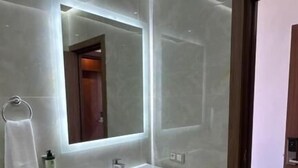 Un baño moderno con un espejo grande, un lavabo y una cabina de ducha de vidrio.