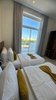 Habitación de hotel con dos camas, un ventanal grande y vista a la ciudad.