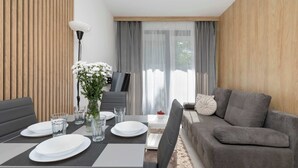 A modern living room with a dining area, grey sofa, and a TV. - Air Conditioned Apartment | Pool | Terrace | Parking (Mielno)