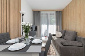 Een moderne woonkamer met een eethoek, een grijze bank en een televisie.