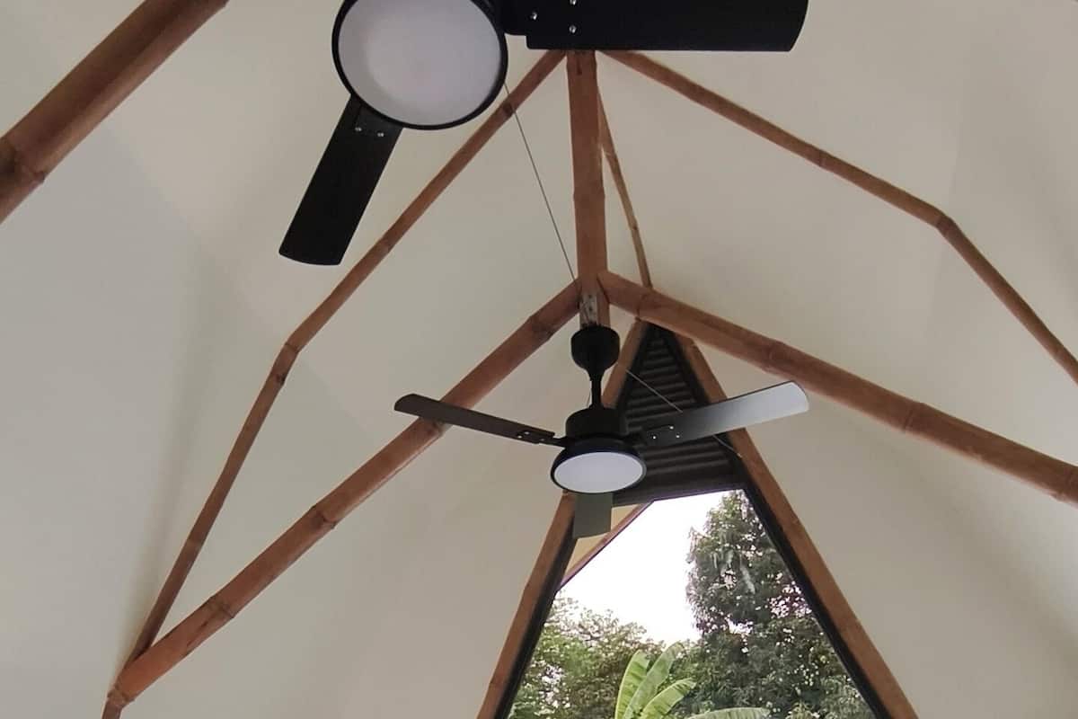 A tent-style room with a bed, ceiling fan, and a view of the outside.