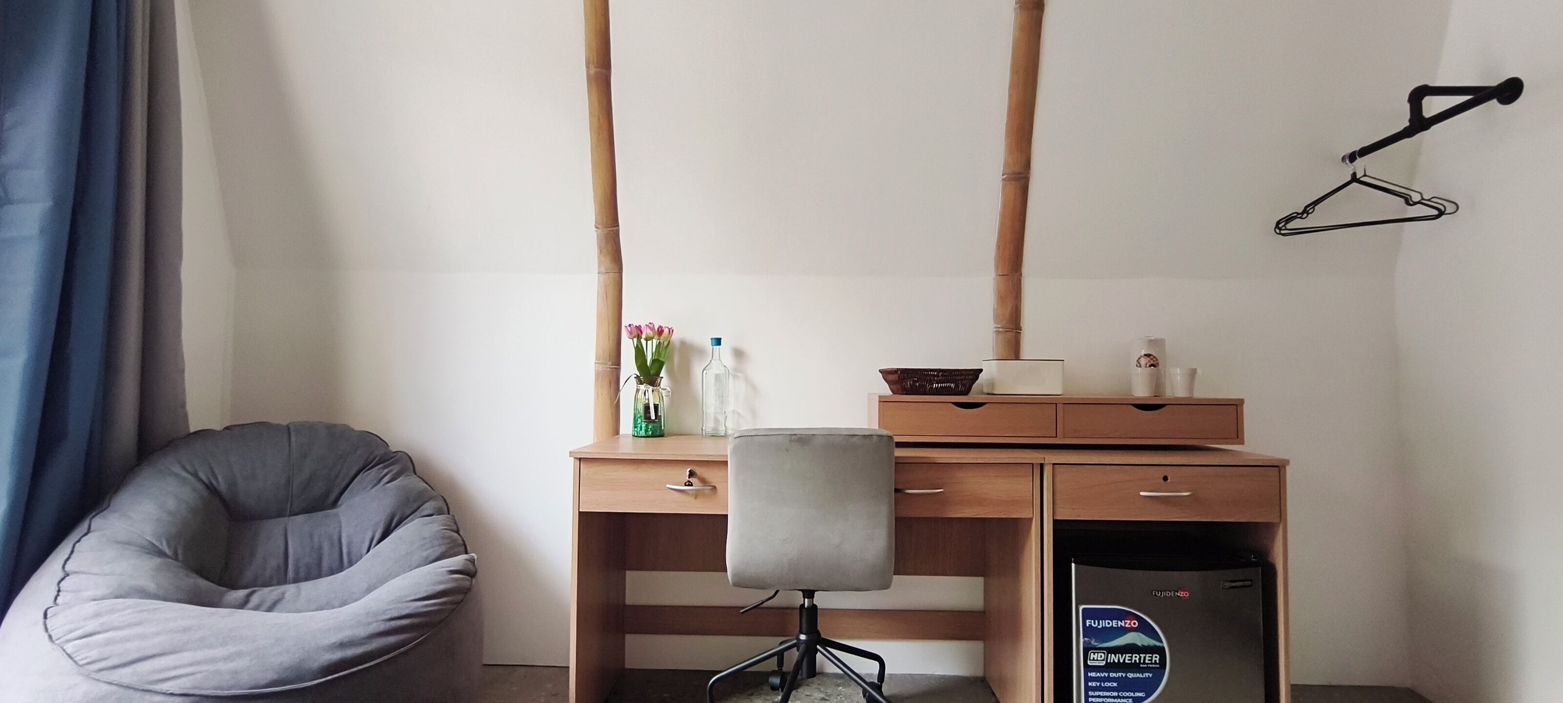 A room with a desk, chair, and a wall-mounted hanger.