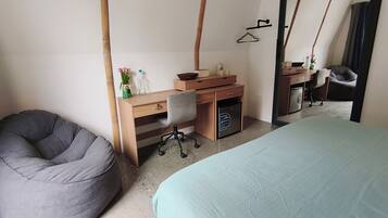Une chambre avec un lit, un bureau et une chaise, un fauteuil poire et un lave-linge.