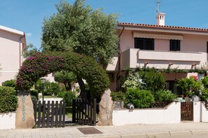 A residential building with a gated entrance, a well-maintained garden, and a clear blue sky. - Nuraghi 42 by Wonderful Italy (Arzachena)