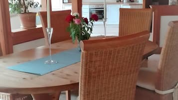 A dining table with chairs, a vase with flowers, and a potted plant.