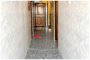 Un pasillo con una puerta de madera, un felpudo rojo y un poste negro.