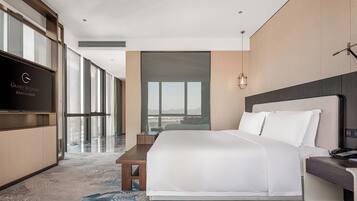 Habitación de hotel con una cama grande, un escritorio, un televisor y vistas de la ciudad.