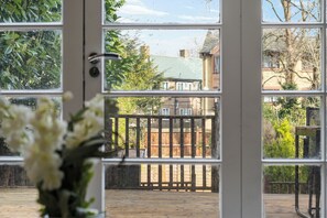 A view through a window with a wooden deck, a metal gate, and a house in the background. - Hidden Gem 15 mins to London Bridge slps 6 (London)