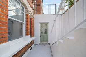A narrow alleyway with a green door, white walls, and a brick building on one side. - Hidden Gem 15 mins to London Bridge slps 6 (London)
