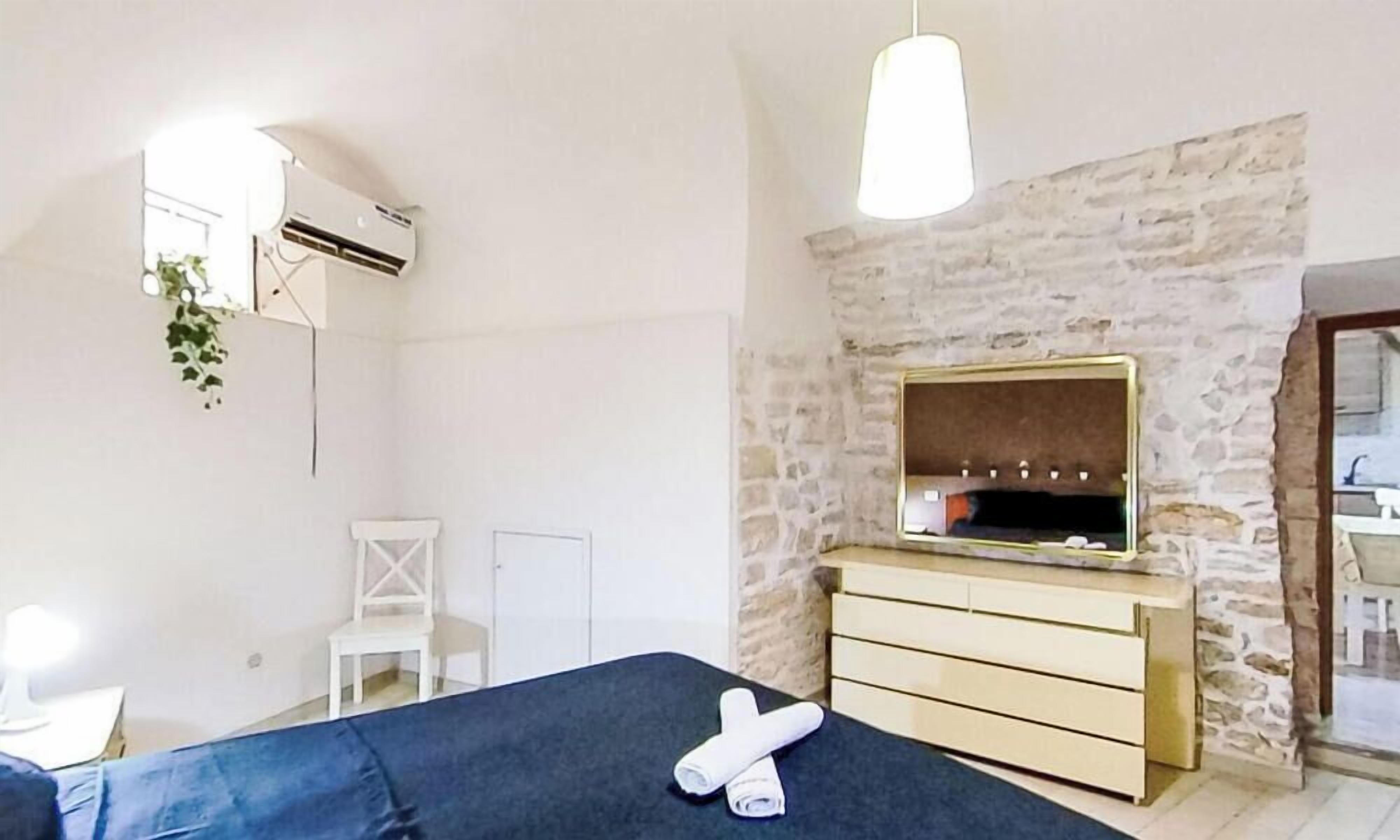 A bedroom with a bed, a dresser, a mirror, and a hanging plant.