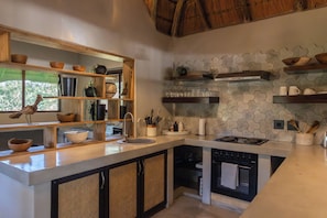 A modern kitchen with wooden shelves, a built-in stove, and a view of the outdoors.