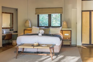 Un dormitorio ordenado con cama, mesitas de noche, un escritorio y una silla.