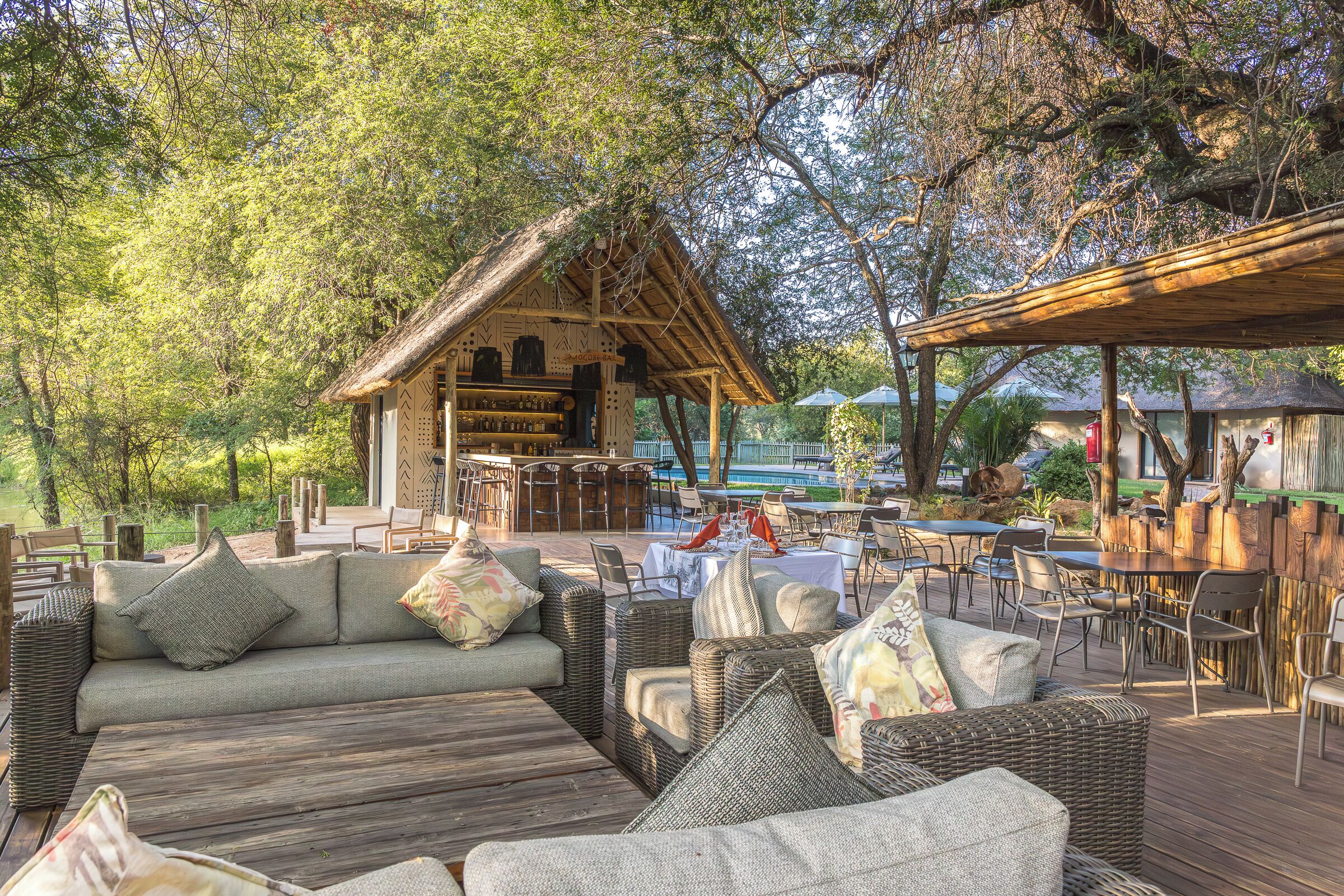 An outdoor seating area with wicker furniture and a thatched-roof structure.
