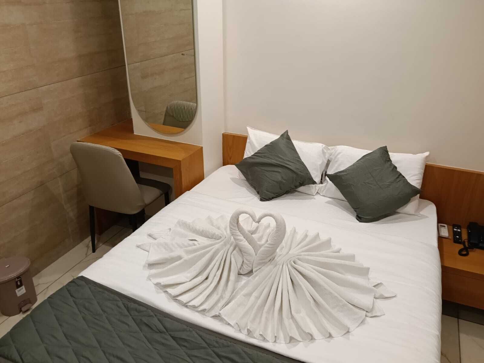 Una habitación de hotel con cama, escritorio, silla, espejo y teléfono.