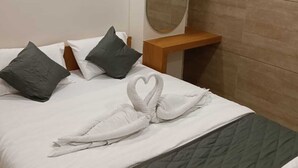 Ein Hotelzimmer mit Bett, Kissen, Nachttisch, Spiegel und Klimaanlage.