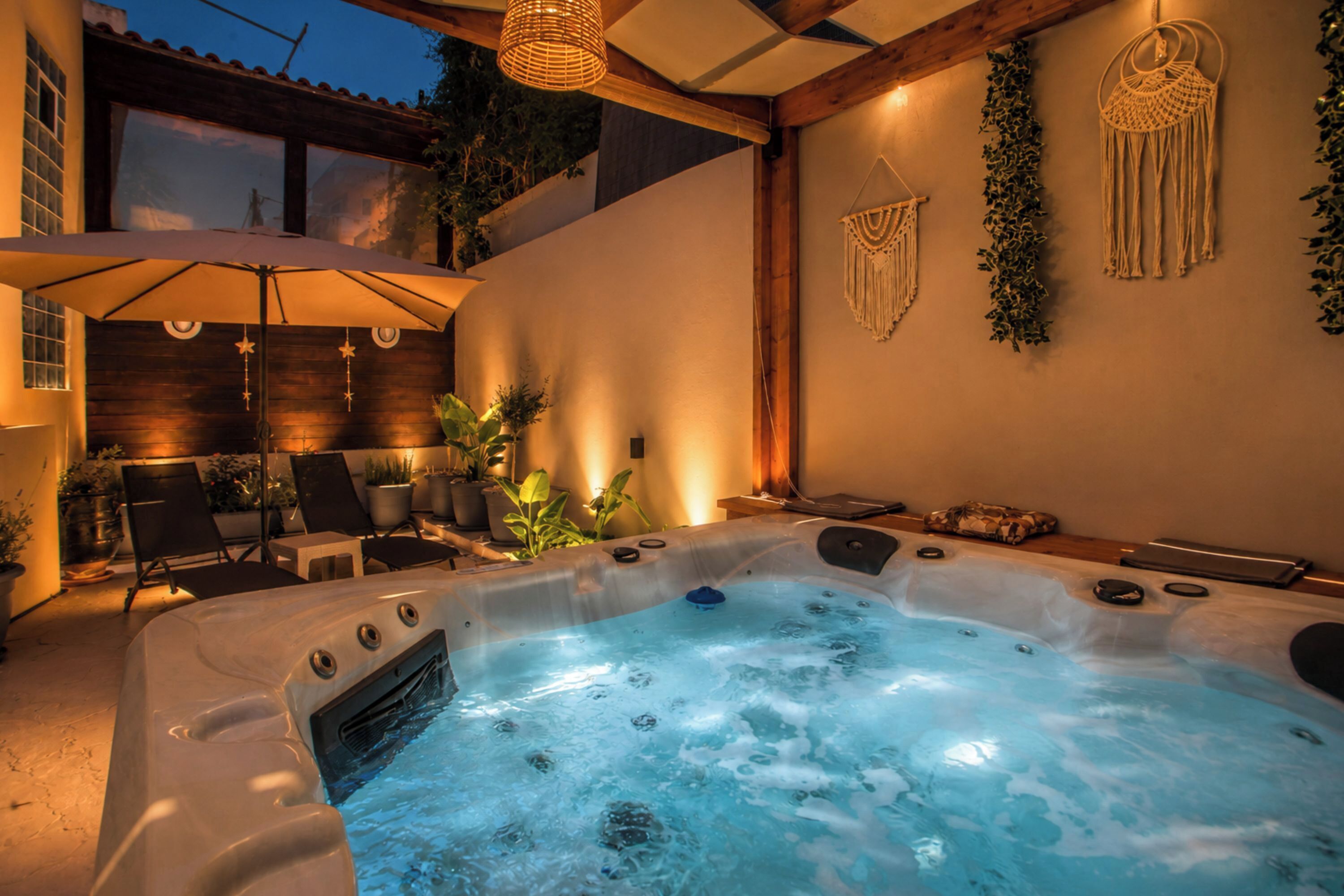 A hot tub with a wooden deck, lounge chairs, and a macrame wall decoration.