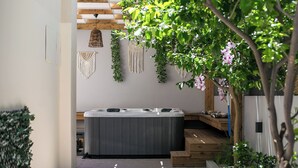Ein Wellnessbereich mit Whirlpool, Holzstufen, Wandbehängen aus Makramee und viel Grün.