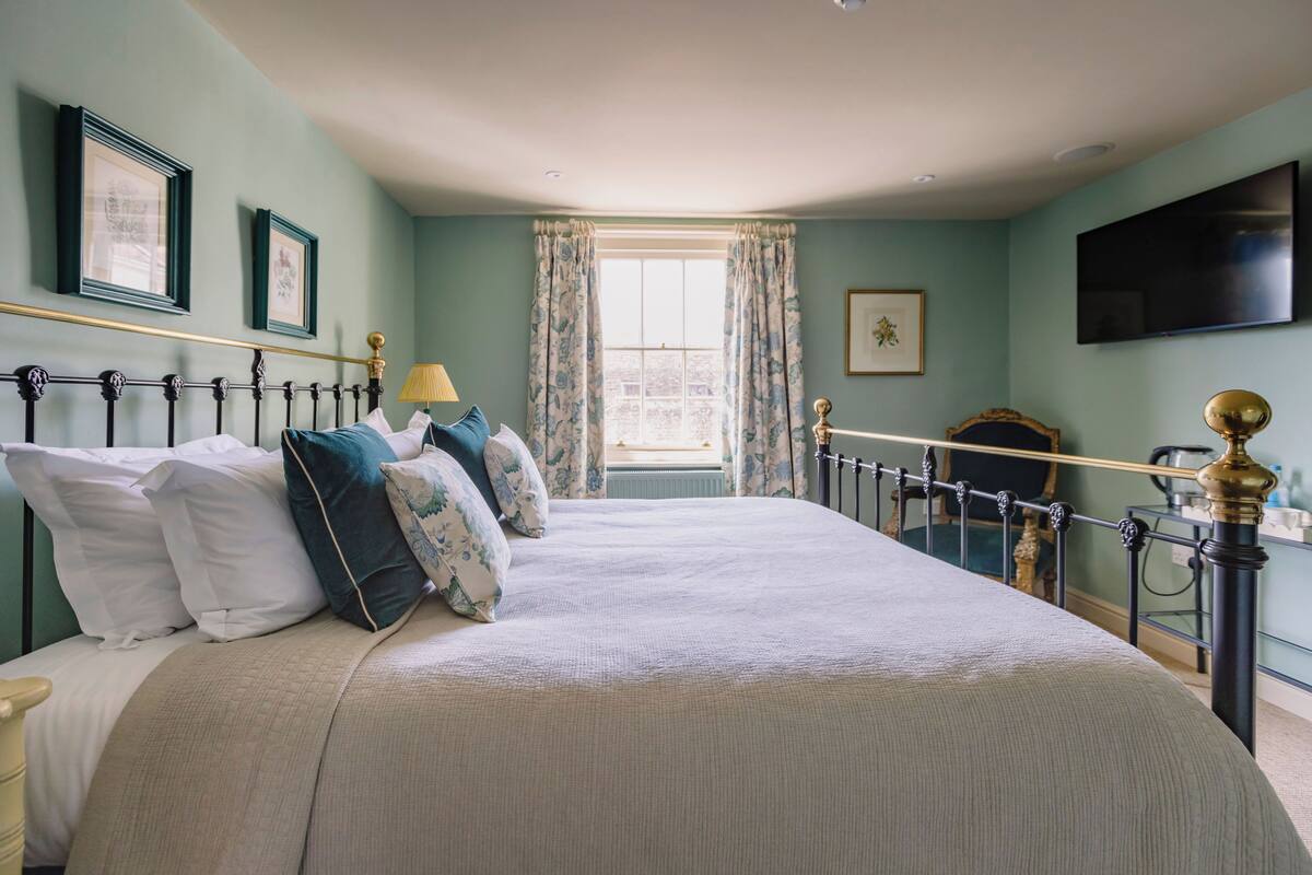 A neatly made bed with a headboard, a bedside table, and a lamp.