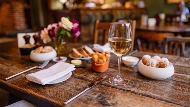 A wooden table with a wine glass, bread, and dessert. - The Bildeston Crown (Bildeston)