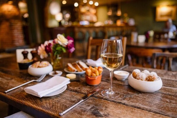 Uma mesa de madeira com uma taça de vinho, pão e sobremesa.