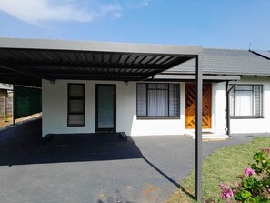 Ein modernes, zweistöckiges Haus mit ĂŒberdachter Veranda, EingangstĂŒr und Garage.