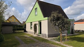 Ein zweistöckiges Haus mit grüner Dachbegrünung und einer Ziegelaußenwand, umgeben von einem gepflegten Rasen und einem gepflasterten Einfahrt.