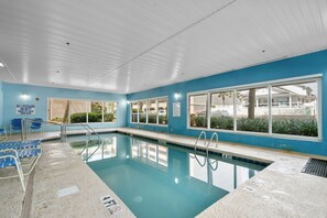 En indendørs swimmingpool med tydelig skiltning, vinduer og en redningsstation.