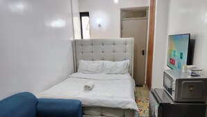 Ein Hotelzimmer mit einem Bett, einem blauen Sofa, einem Fernseher und einer Mikrowelle.
