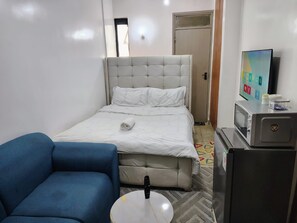 Ein Hotelzimmer mit einem Bett, einem blauen Sofa, einem Fernseher und einer Mikrowelle.